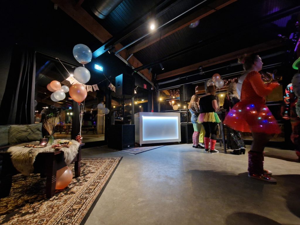 DJ aan het draaien tijdens een verjaardag feest met dansende gasten en professionele verlichting