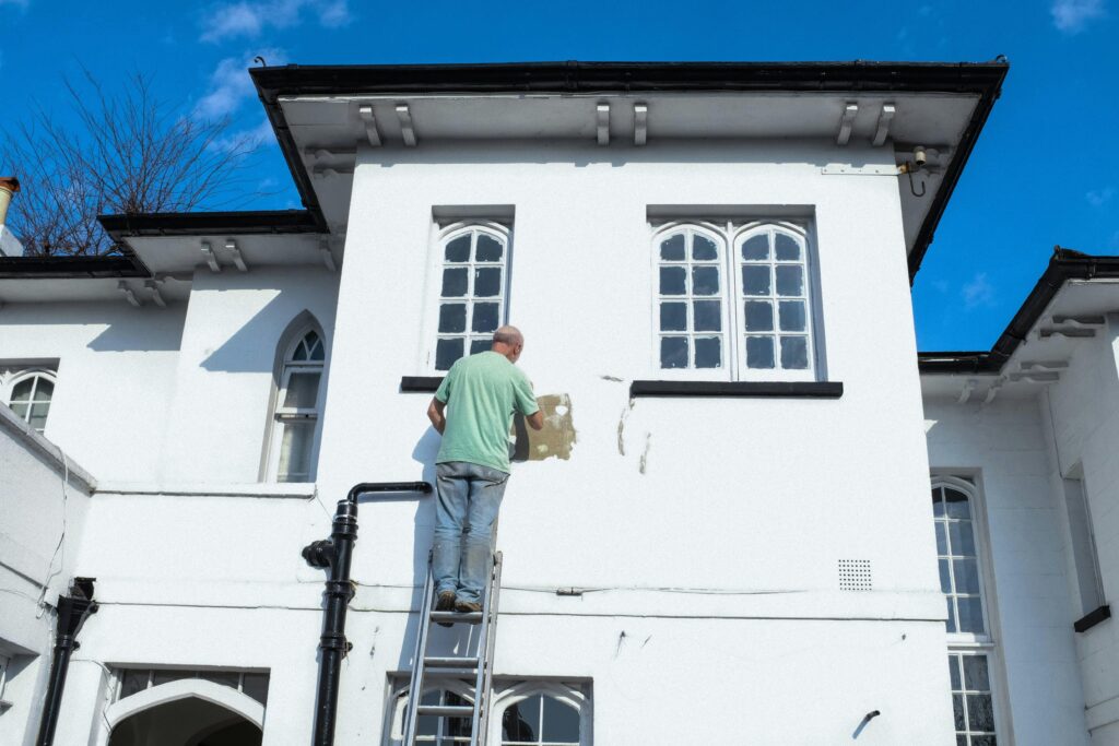Buitenschilder aan het werk op houten gevel, waarschuwingstekenen dat nieuw schilderwerk nodig is